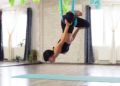 Adult woman practices anti-gravity yoga position in studio