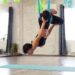 Adult woman practices anti-gravity yoga position in studio