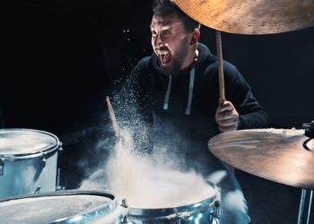 Drummer rehearsing on drums before rock concert. Man recording music on drum set in studio